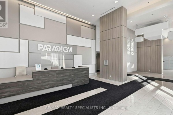 A spacious condo lobby with a modern front desk, wood paneling, and geometric wall art. - 2004 - 2093 Fairview Street, Burlington