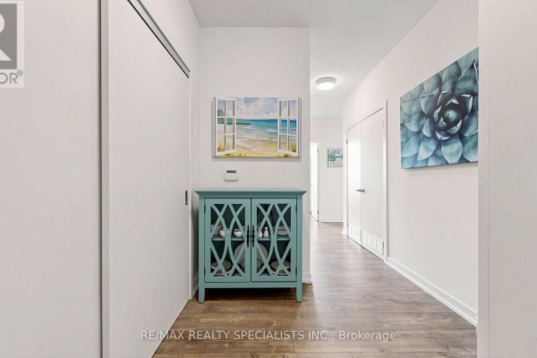 Apartment hallway with hardwood floors, white doors, and decorative wall art and furniture. - 2004 - 2093 Fairview Street, Burlington