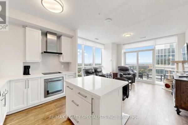 Open-concept kitchen and living area with white cabinets, stainless steel appliances, and city views. - 2004 - 2093 Fairview Street, Burlington