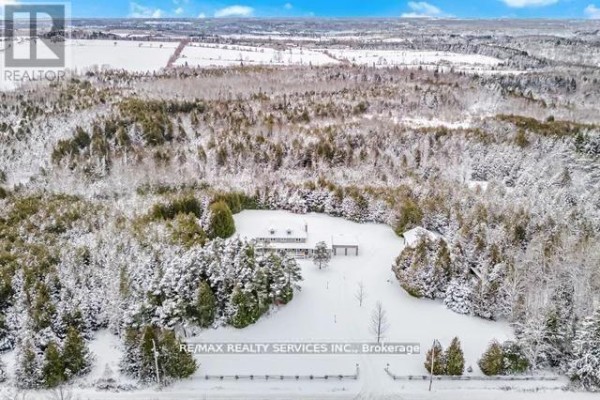 House with detached garage, driveway, and wooded lot in snow - 20040 Kennedy Road, Caledon