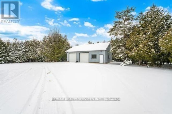 Detached two-bay garage with side door and window in snowy landscape - 20040 Kennedy Road, Caledon