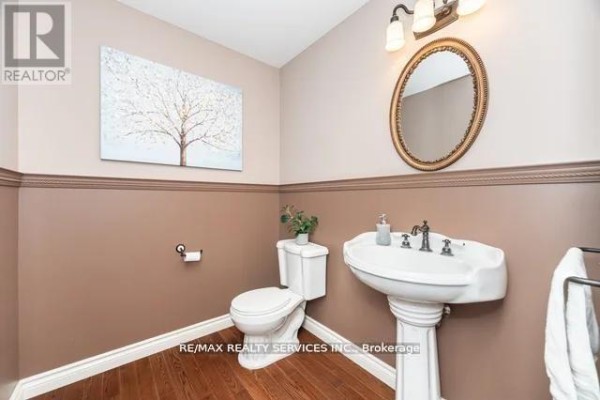 Bathroom with pedestal sink, toilet, framed mirror, hardwood floors - 20040 Kennedy Road, Caledon