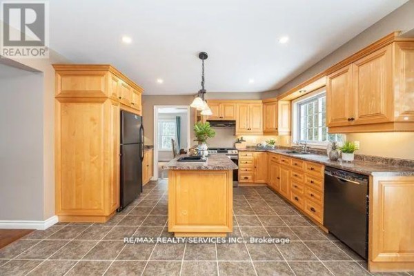 Kitchen with wood cabinets, island, black appliances, and tile floors - 20040 Kennedy Road, Caledon