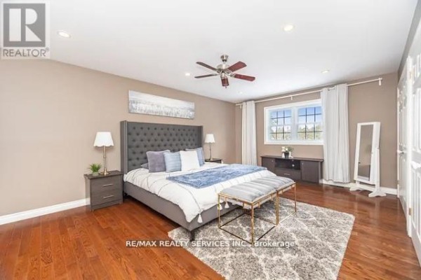 Bedroom with hardwood floors, tufted bed, ceiling fan, and large window - 20040 Kennedy Road, Caledon