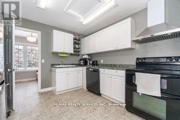 Kitchen with white cabinets, black appliances, stainless steel range hood, tile floors - 20040 Kennedy Road, Caledon