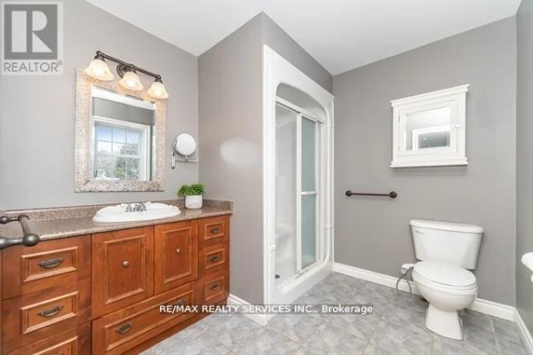 Bathroom with wooden vanity, single sink, mirror, shower stall, and tile floors - 20040 Kennedy Road, Caledon