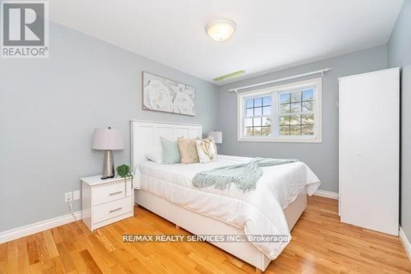 Bedroom with hardwood floors, window, nightstand, and white wardrobe - 20040 Kennedy Road, Caledon