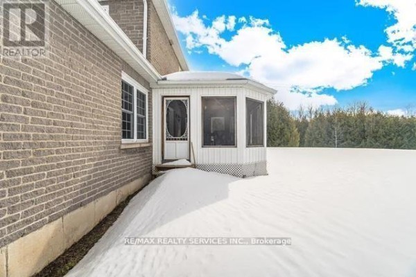 Brick house exterior with enclosed porch and snowy yard - 20040 Kennedy Road, Caledon