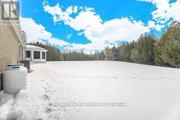 Brick house with screened porch, large snow-covered yard, and trees - 20040 Kennedy Road, Caledon