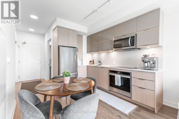 Open concept kitchen and dining area with a round table and four grey chairs. - 2005 - 10 Deerlick Court, Toronto