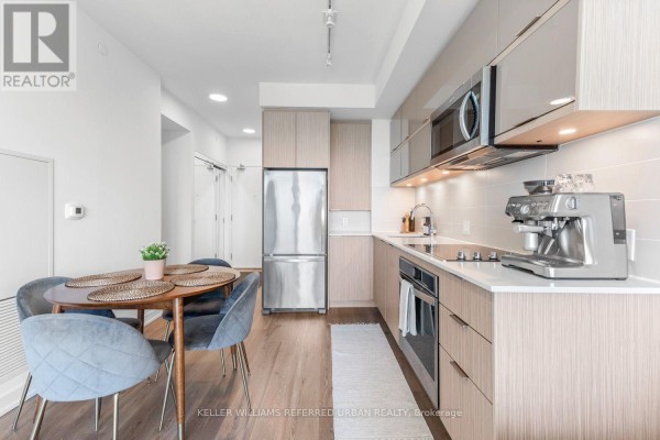 Compact kitchen with wood-grain cabinets, stainless steel appliances, and a seating area. - 2005 - 10 Deerlick Court, Toronto