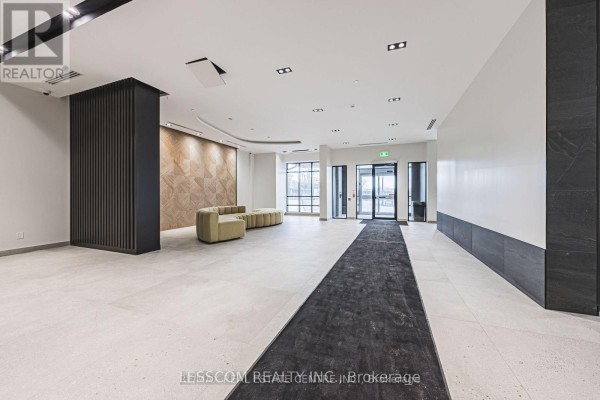 Spacious lobby with light tiled floors, modern seating, and glass doors. - 2005 - 225 Malta Avenue, Brampton