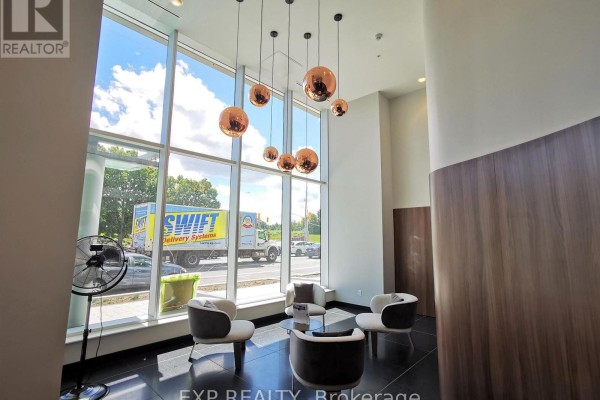Lobby seating area with four chairs and a glass coffee table in front of floor-to-ceiling windows. - 2005 - 805 Carling Avenue, Ottawa