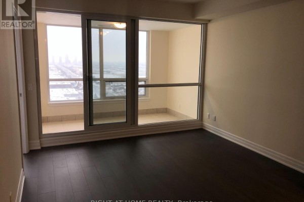 Living room area with dark wood floors, beige walls, and a balcony entrance. - 2005 - 9075 Jane Street, Vaughan