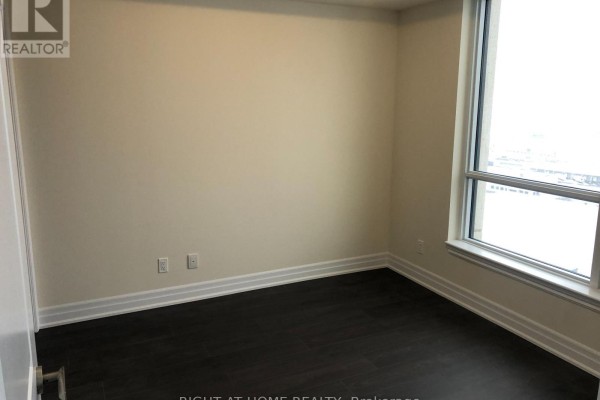 Empty bedroom with dark wood floors, beige walls, and a large window. - 2005 - 9075 Jane Street, Vaughan