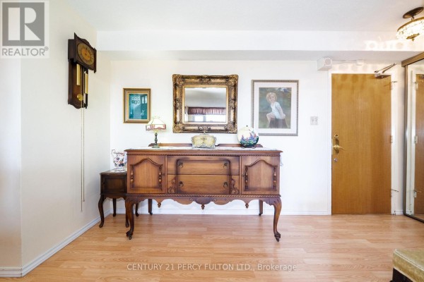 Hallway entrance with a wooden sideboard, mirror, artwork, pendulum clock, and a wooden door. - 2006 - 1350 York Mills Road, Toronto