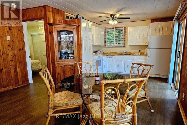 Kitchen and dining area with wood-paneled walls, wicker chairs, and a glass-top table. - 2006 South Beaver Lake Lane, Minden Hills