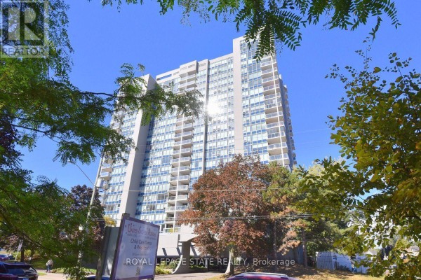 A tall apartment building with balconies partially obscured by leafy trees. - 2007 - 75 Queen Street N, Hamilton