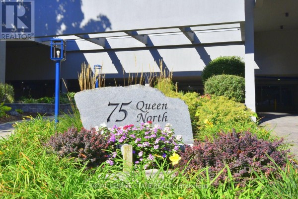 A stone monument with '75 Queen North' etched into it, surrounded by flowers. - 2007 - 75 Queen Street N, Hamilton