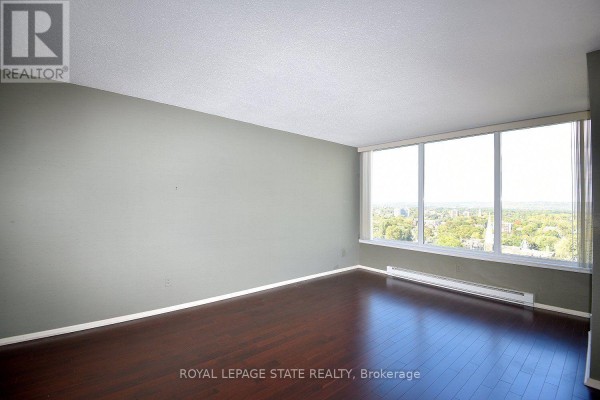An empty room with pale green walls, dark wood floors, and a large window. - 2007 - 75 Queen Street N, Hamilton