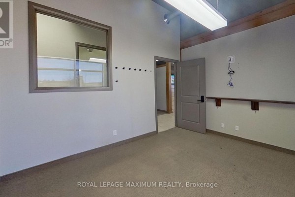 Interior office space with beige carpet, gray door, and window overlooking another room. - 2007 Commerce Pk Drive, Innisfil