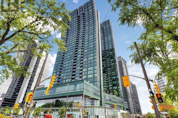 View of two tall green glass condo buildings from street level with trees and traffic lights. - 2008 - 9 Bogert Avenue, Toronto