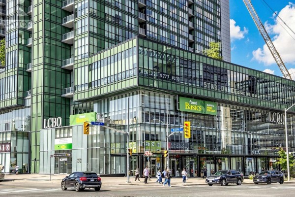 Ground level view of a modern building with glass facade, showing retail stores and street entrance. - 2008 - 9 Bogert Avenue, Toronto