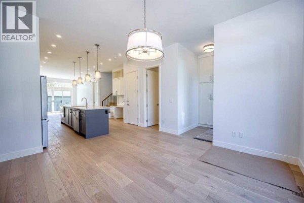 Kitchen with a large island, stainless steel appliances, and white cabinetry and backsplash. - 2008 26a Street Sw, Calgary