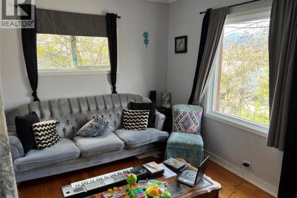 Living room featuring a grey tufted sofa with black and white patterned pillows, and a teal accent chair. - 2008 Topping Street, Trail
