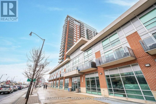 Side view of the condo building showing the brick facade and commercial storefronts. - 2009 - 215 Queen Street E, Brampton