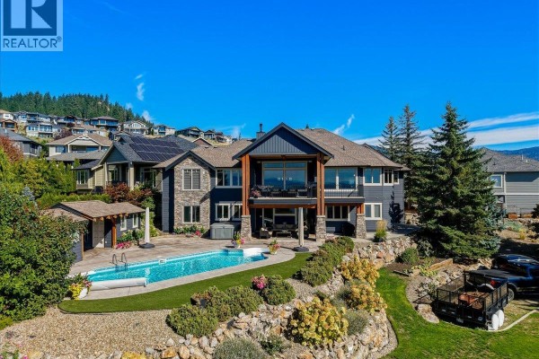 Rear exterior of a two-story house with a swimming pool, hot tub, and covered patio. - 2009 Apex Court, Vernon