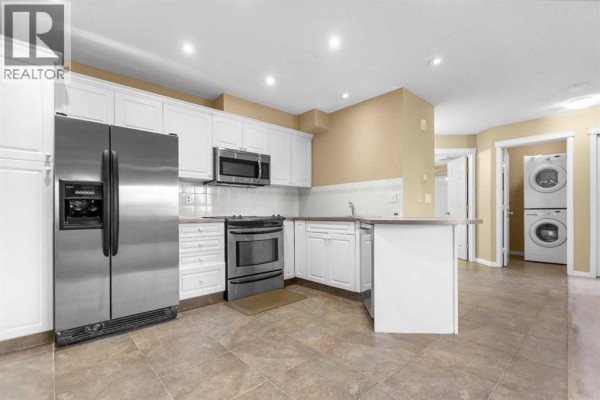 Kitchen with white cabinets, stainless steel appliances, and tile flooring. - 201, 20 Country Hills View Nw, Calgary