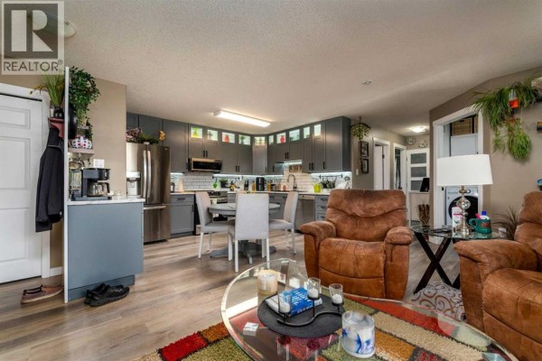 Open-concept living area and kitchen with gray cabinets and a round dining table. - 201, 5102 47 Street, Lloydminster