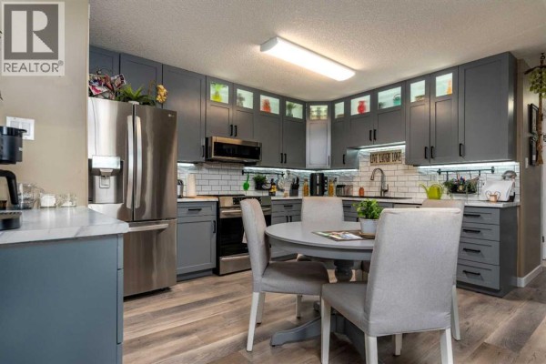 Modern kitchen with gray cabinets, stainless steel appliances, and a gray round dining table. - 201, 5102 47 Street, Lloydminster