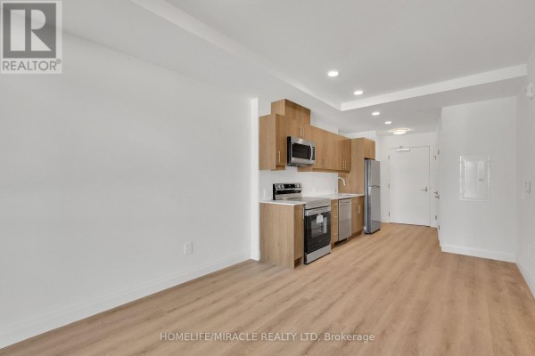 A modern kitchen area with light wood cabinetry, stainless steel appliances, a dishwasher, and a refrigerator. - 201 - 1333 Weber Street E, Kitchener