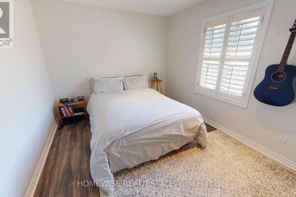 Bedroom with a queen-sized bed, white shutters on the window, and a patterned rug. - 201 - 145 Lansdowne Avenue, Toronto