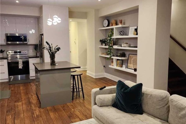 Open concept living area and kitchen with a grey island, stainless steel appliances, and white shelving. - 201 - 15 Ennerdale Road, Toronto