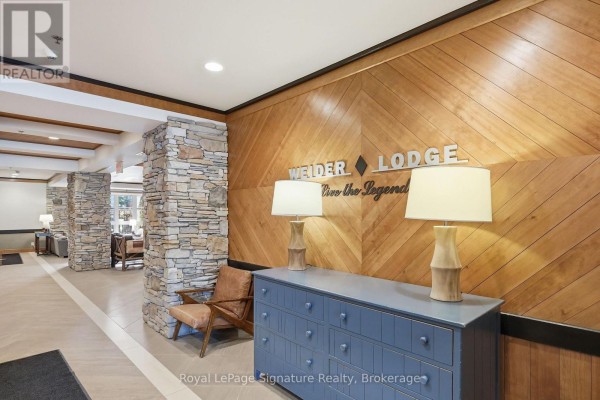 Interior lobby with stone columns, wood-paneled walls, and a blue dresser with lamps. - 201 - 152 Jozo Weider Boulevard, Blue Mountains
