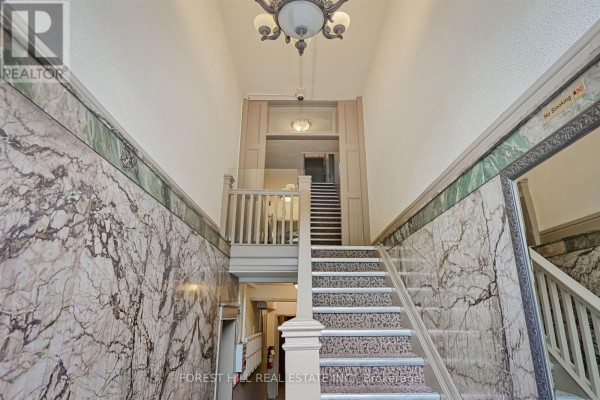 Interior building lobby with marble walls, staircase, and chandelier. - 201 - 333 Harbord Street, Toronto