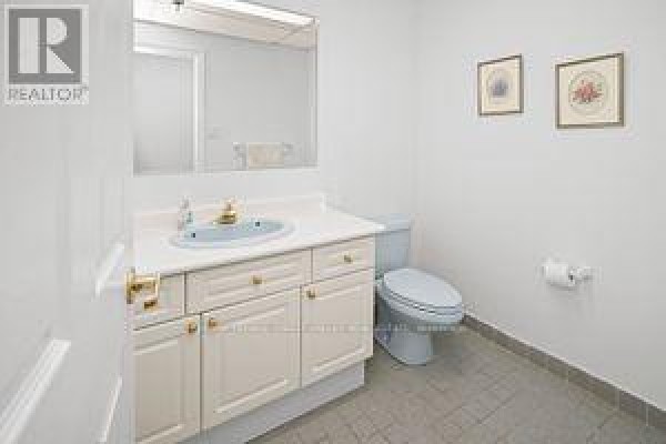 Small bathroom with light blue toilet, white vanity, blue sink, and mirror above. - 201 - 335 Renfrew Drive, Markham