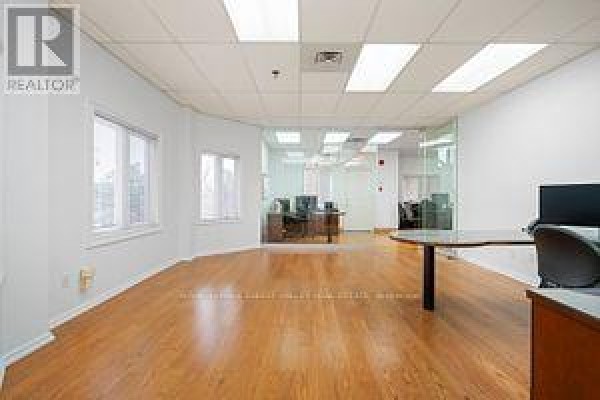 Corner office view with glass-walled offices, windows, wood floors, and desks. - 201 - 335 Renfrew Drive, Markham