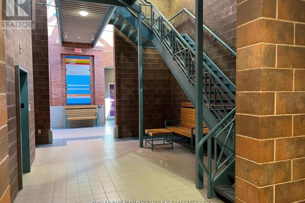 Interior hallway with a metal staircase, benches, and tiled floor. - 201 - 342 Erie Street, Stratford