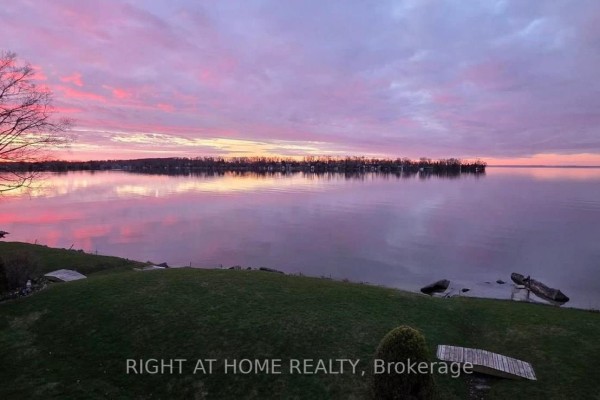 Purple and pink sunset over a calm lake with a distant shoreline and silhouetted trees. - 201 - 43 Olive Crescent, Orillia