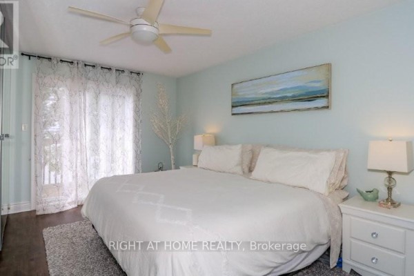 Living room with a large white sofa, coffee table, fireplace, and view of a balcony and lake. - 201 - 43 Olive Crescent, Orillia