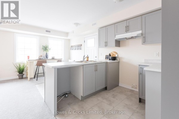 Living room with sofa, coffee table, chairs, and a dining counter with stools. - 201 - 48 Maple Avenue, Asphodel Norwood