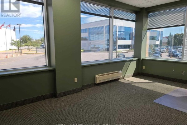 Empty office room with green walls, carpet, and large windows overlooking a parking lot. - 201 - 50 Acadia Avenue, Markham