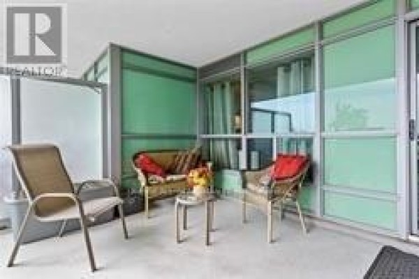 Spacious balcony with seating, large windows, and a glass door. - 201 - 60 Fairfax Crescent, Toronto