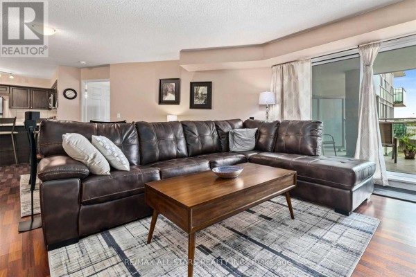 Open-concept living and dining area with hardwood floors and contemporary furniture. - 201 - 60 Fairfax Crescent, Toronto