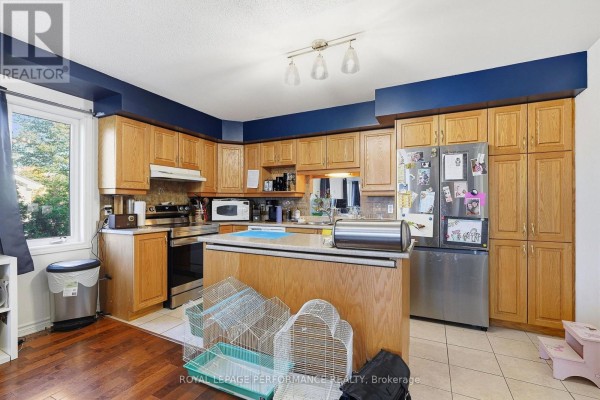 U-shaped kitchen with light wood cabinets, stainless steel appliances, dark blue accent walls, and a center island. - 201 - 770 Principale Street, Casselman
