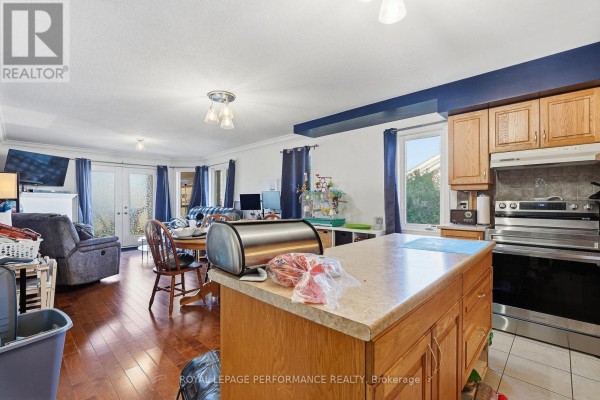 Open-concept living and dining area with hardwood floors, a kitchen island, and patio doors leading outside. - 201 - 770 Principale Street, Casselman